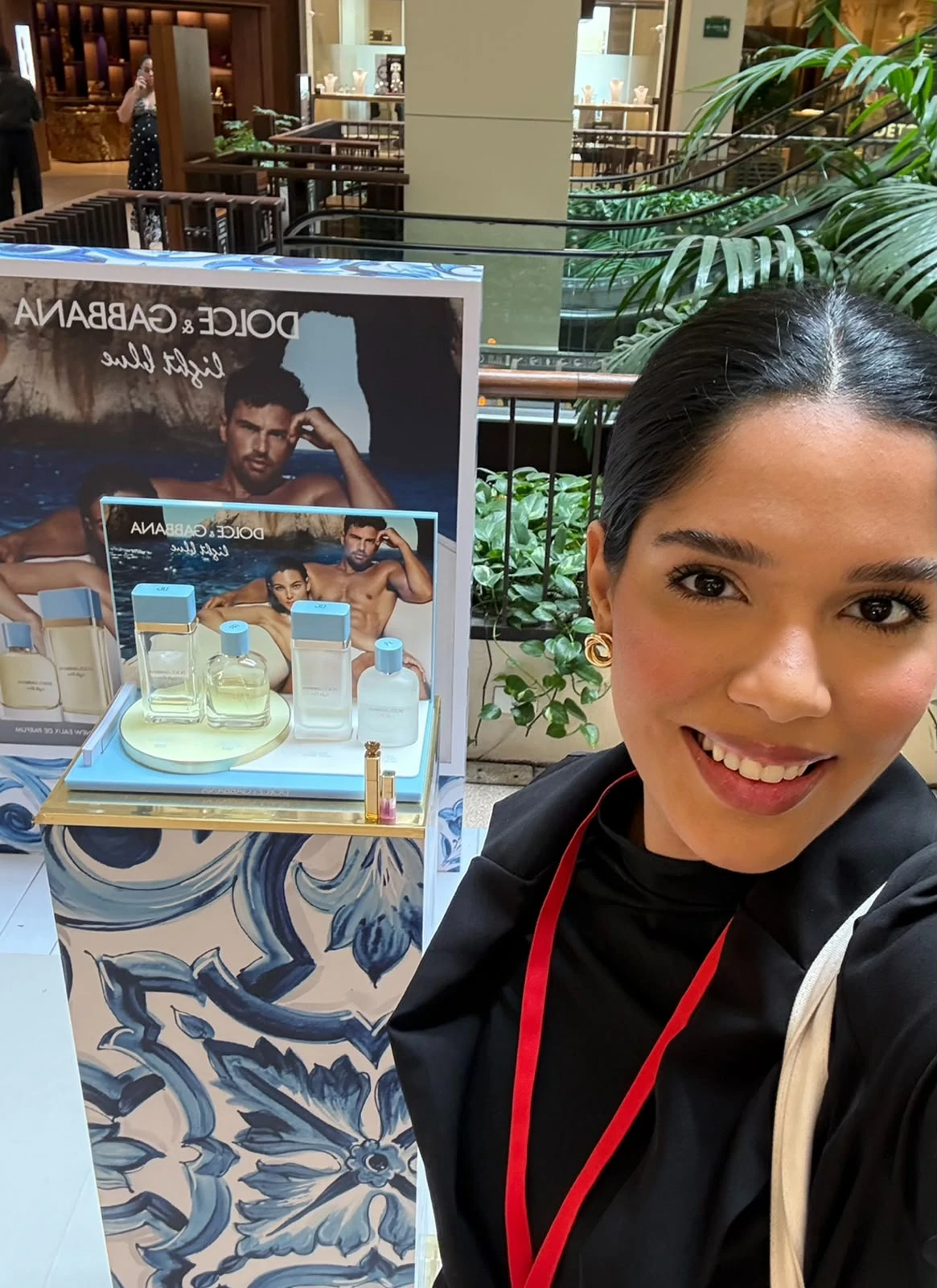 Profissional ao lado de um expositor de perfumes no ponto de venda