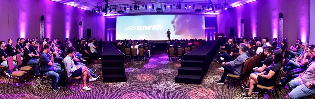 Público diante do palco da convenção Olympikus com iluminação roxa