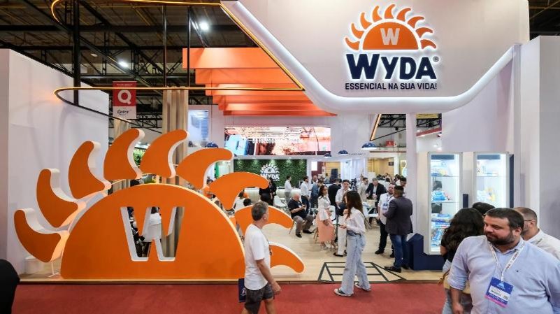 Visitantes no stand branco e laranja da Wyda em feira