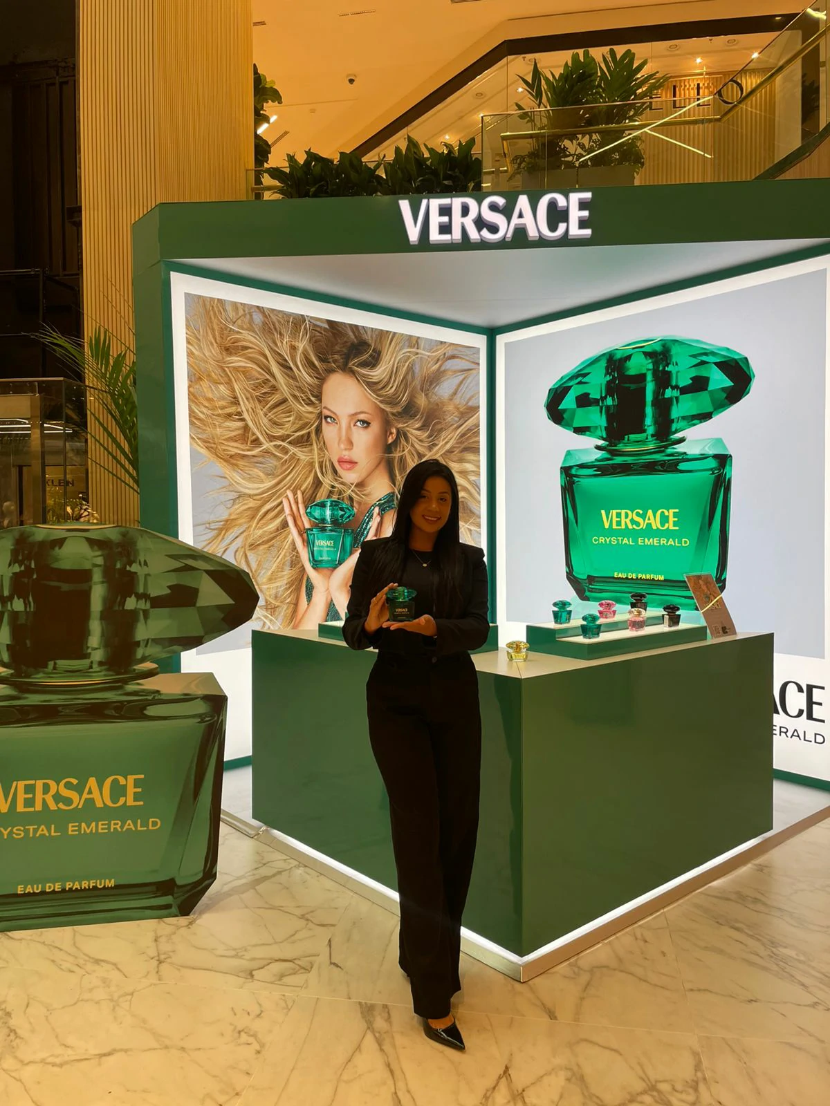 Profissional com perfume diante do stand verde Versace Crystal Emerald